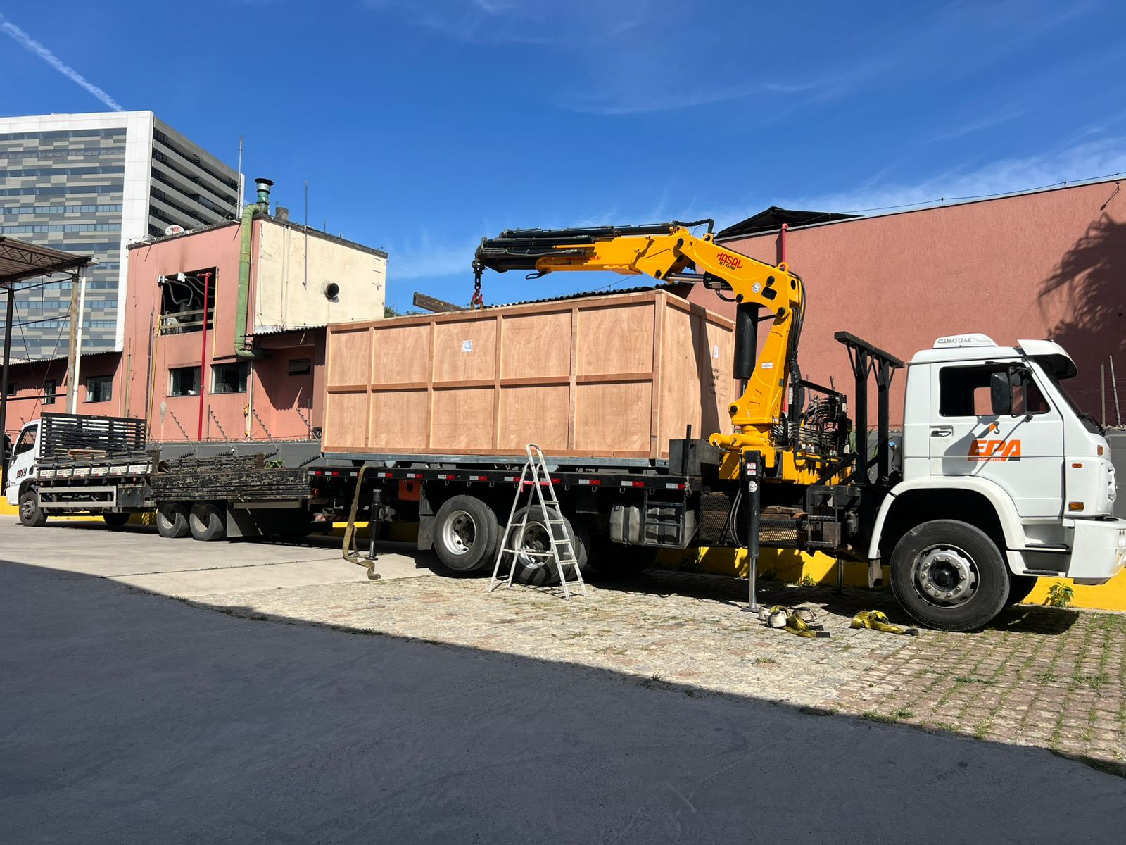 Caminhao da EPA Transportes ao lado de equipamento industrial
